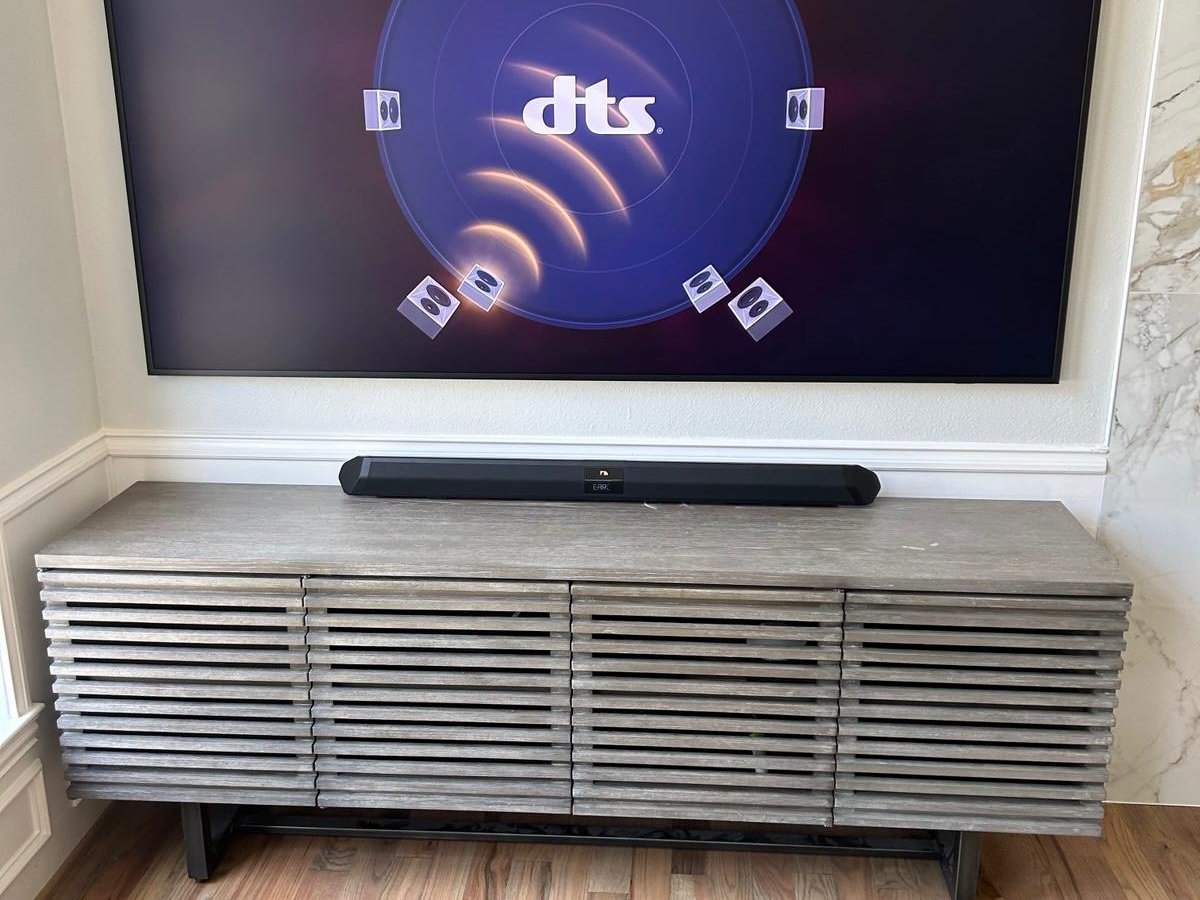 TV with soundbar mounted on a wall above a credenza